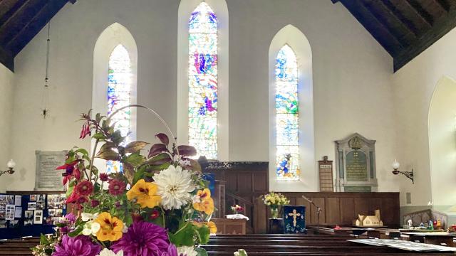 flowers in the foreground and Colmonell Church stained glass windows in the background