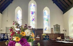 flowers in the foreground and Colmonell Church stained glass windows in the background